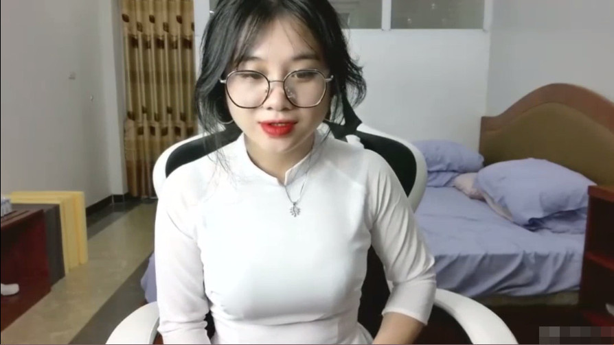 Gadis kecil yang lucu dengan ao dai dan kacamata setelah kembali dari sekolah